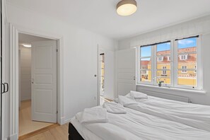 Un dormitorio con cama, ventana con vista y puerta que da a otra habitación.