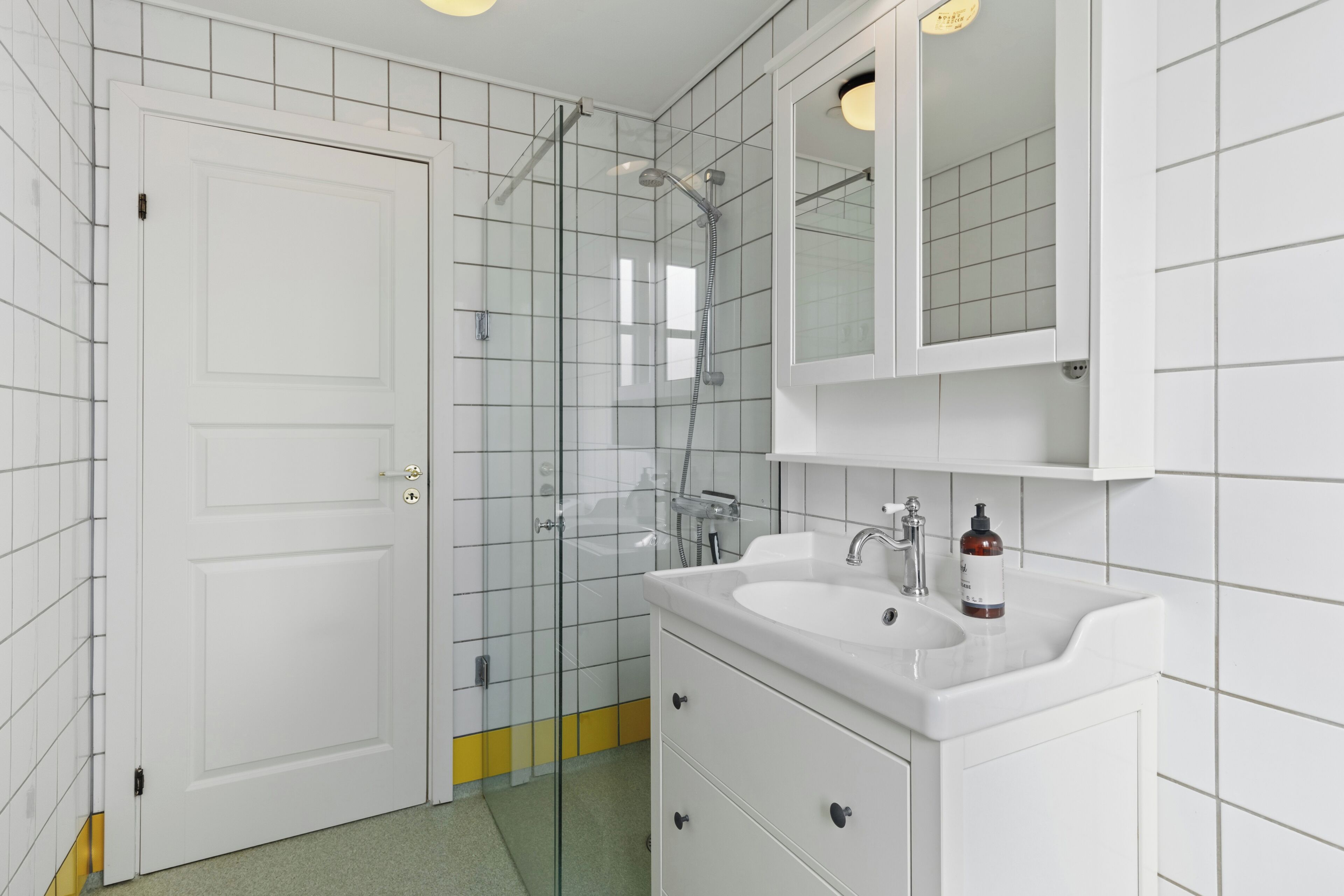 A bathroom with a white sink, mirror, and glass shower enclosure.