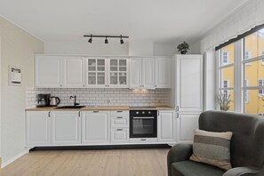 Een moderne keuken met witte kastjes, een houten aanrechtblad en een inbouwoven.