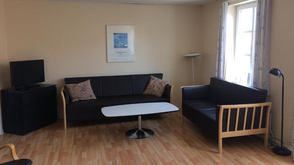 A living room with a sofa, a coffee table, a TV on a stand, and a floor lamp.