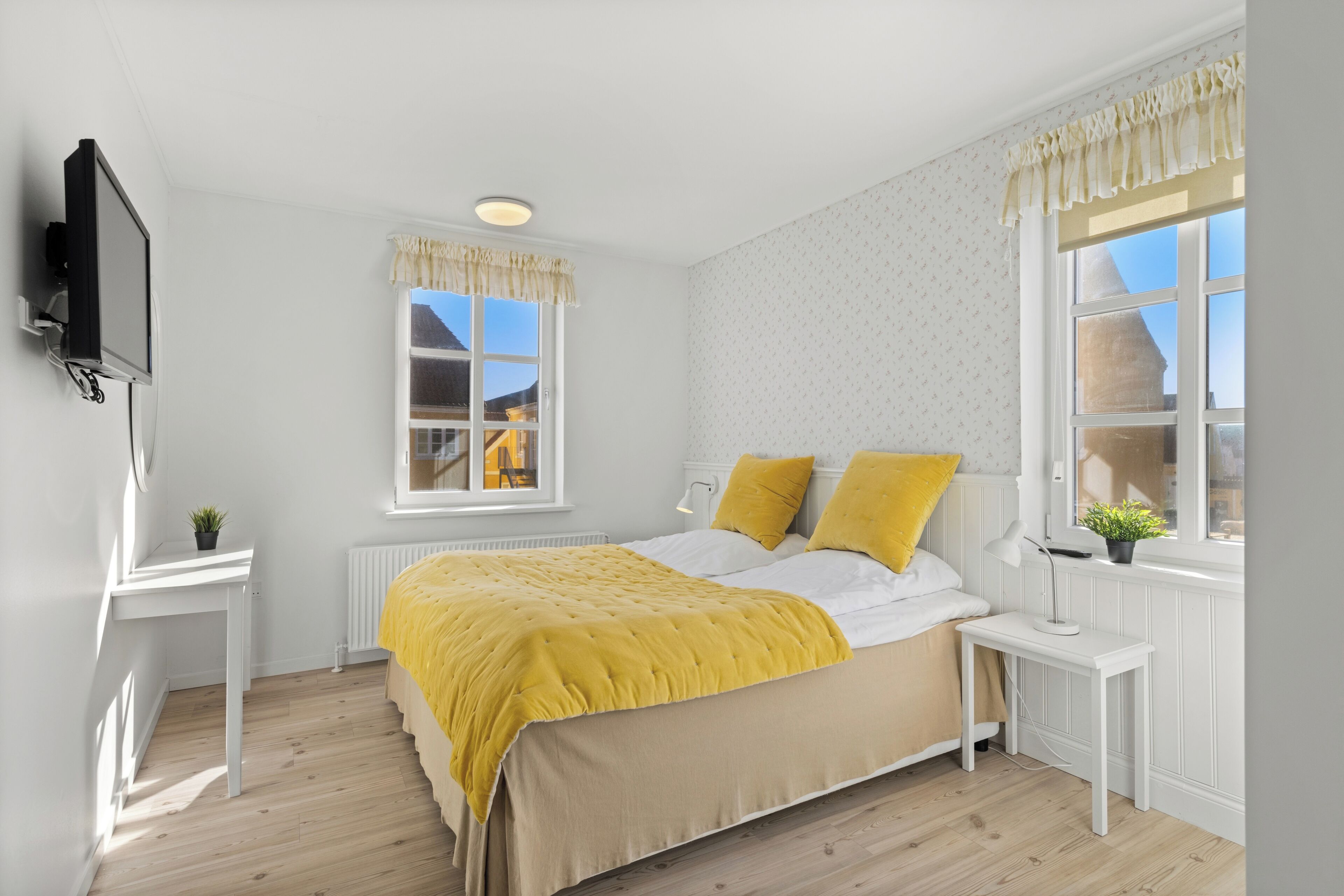 A bedroom with a bed, bedside tables, a TV, and a window with a view.