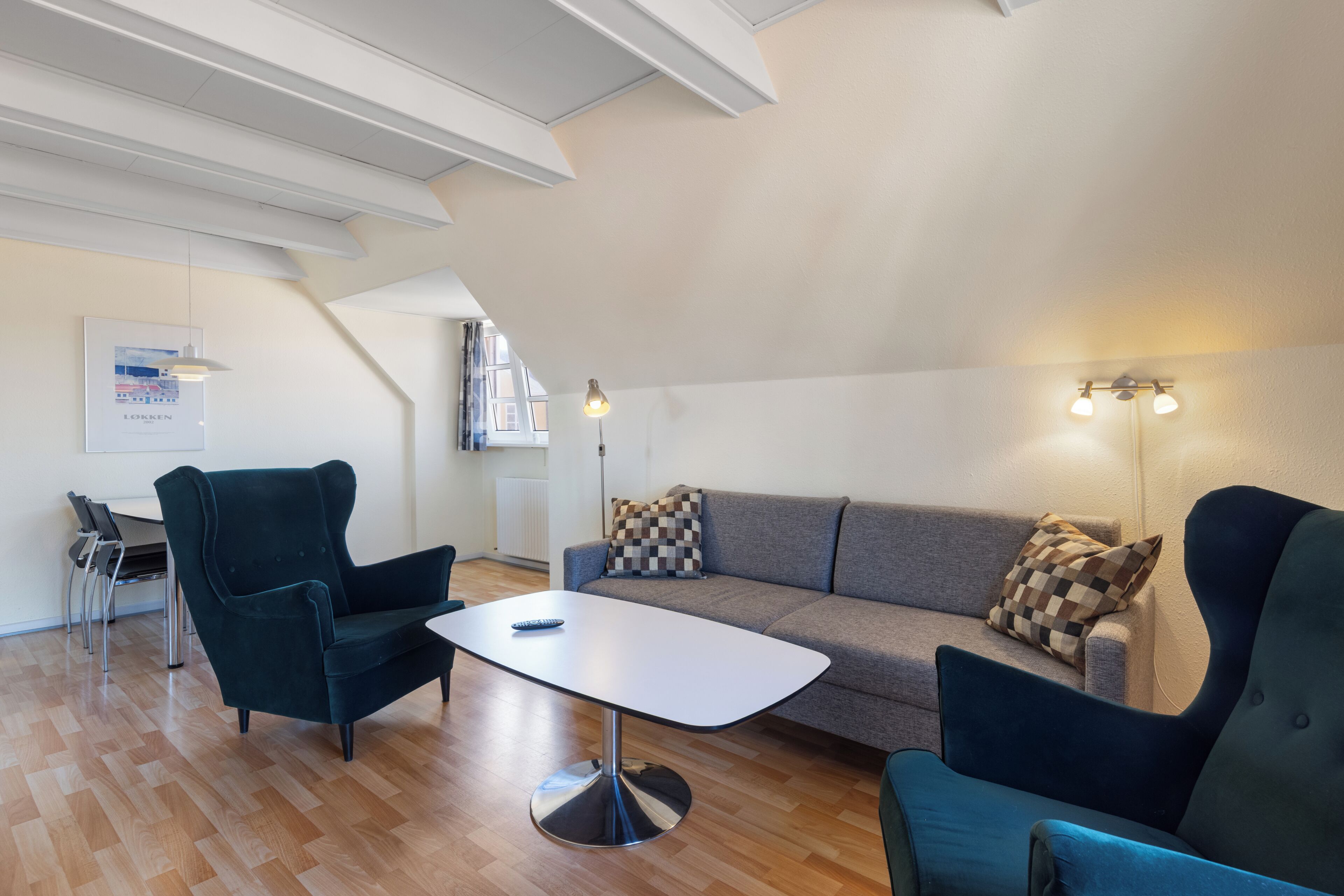 A modern living room with a sofa, two armchairs, a coffee table, and a dining area with chairs.