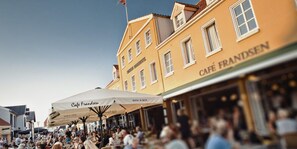 Een bruisend terras met tafels en parasols, omringd door historische gebouwen.