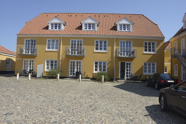 A yellow building with a tiled roof, multiple windows, and balconies. - Løkken Badehotel - Apartment Hotel (Lokken)