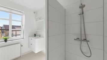 Ein modernes Badezimmer mit Dusche, Fenster, Heizkörper und Waschbecken.