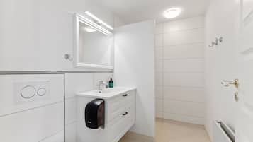 Een moderne badkamer met een witte wastafel, een spiegel, een handdroger en een toilet.