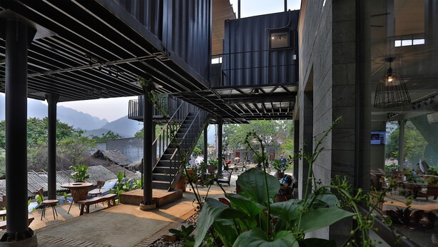 Una terraza exterior con un diseño arquitectónico moderno, que incluye una escalera, zonas de estar y plantas en macetas.