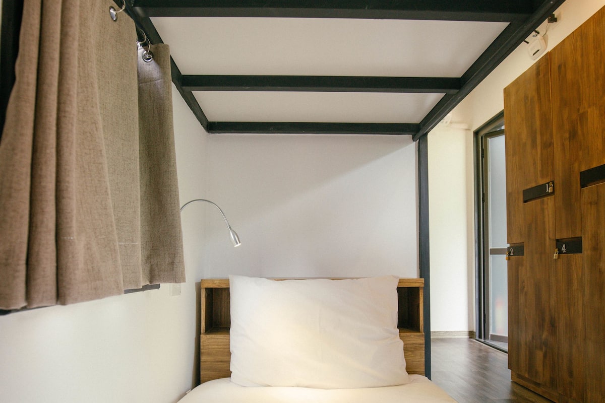 A bedroom with a bed, wooden headboard, a nightstand, a lamp, and a wardrobe.