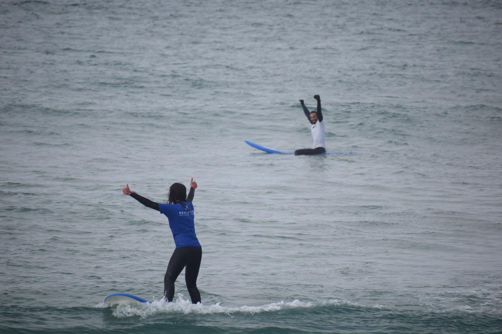 Dos personas surfeando en un mar tranquilo.