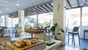 Un bufé de desayuno con pan, bollería y una cesta de mimbre.