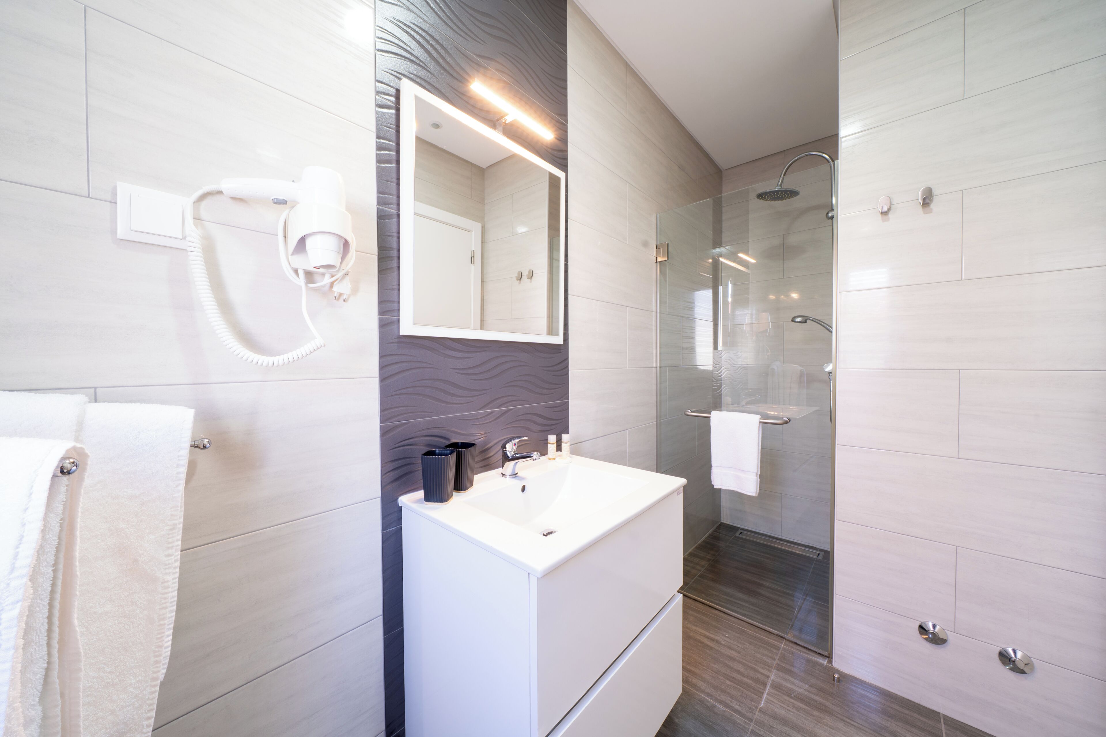 A modern bathroom with a vanity, mirror, and shower.