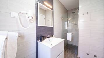 A modern bathroom with a vanity, mirror, and shower.
