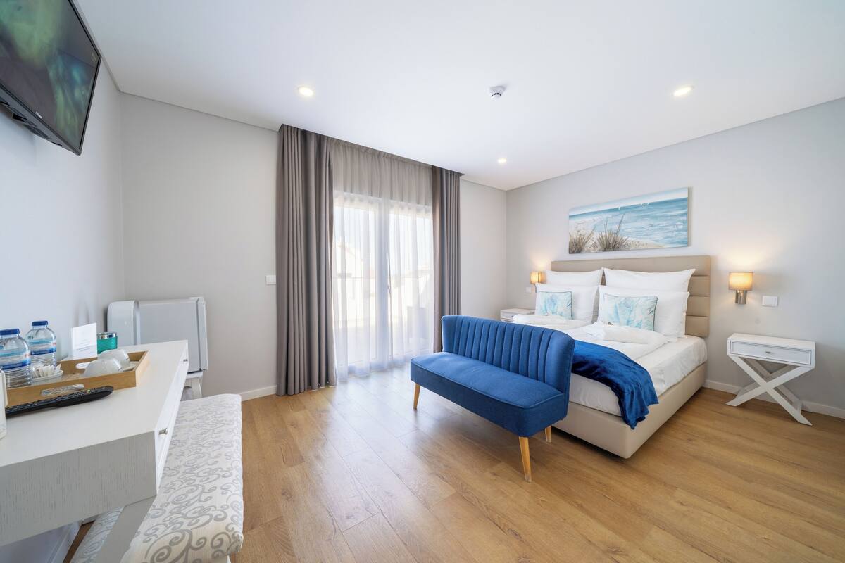 Een moderne hotelkamer met een bed, nachtkastje en bureau met stoel.