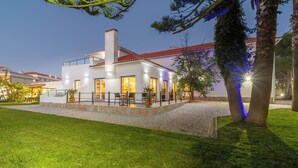 Una casa moderna con un patio de piedra, mobiliario exterior e iluminación en la entrada.