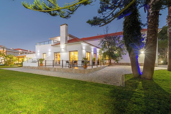 A modern house with a stone patio, outdoor seating, and a well-lit entrance.