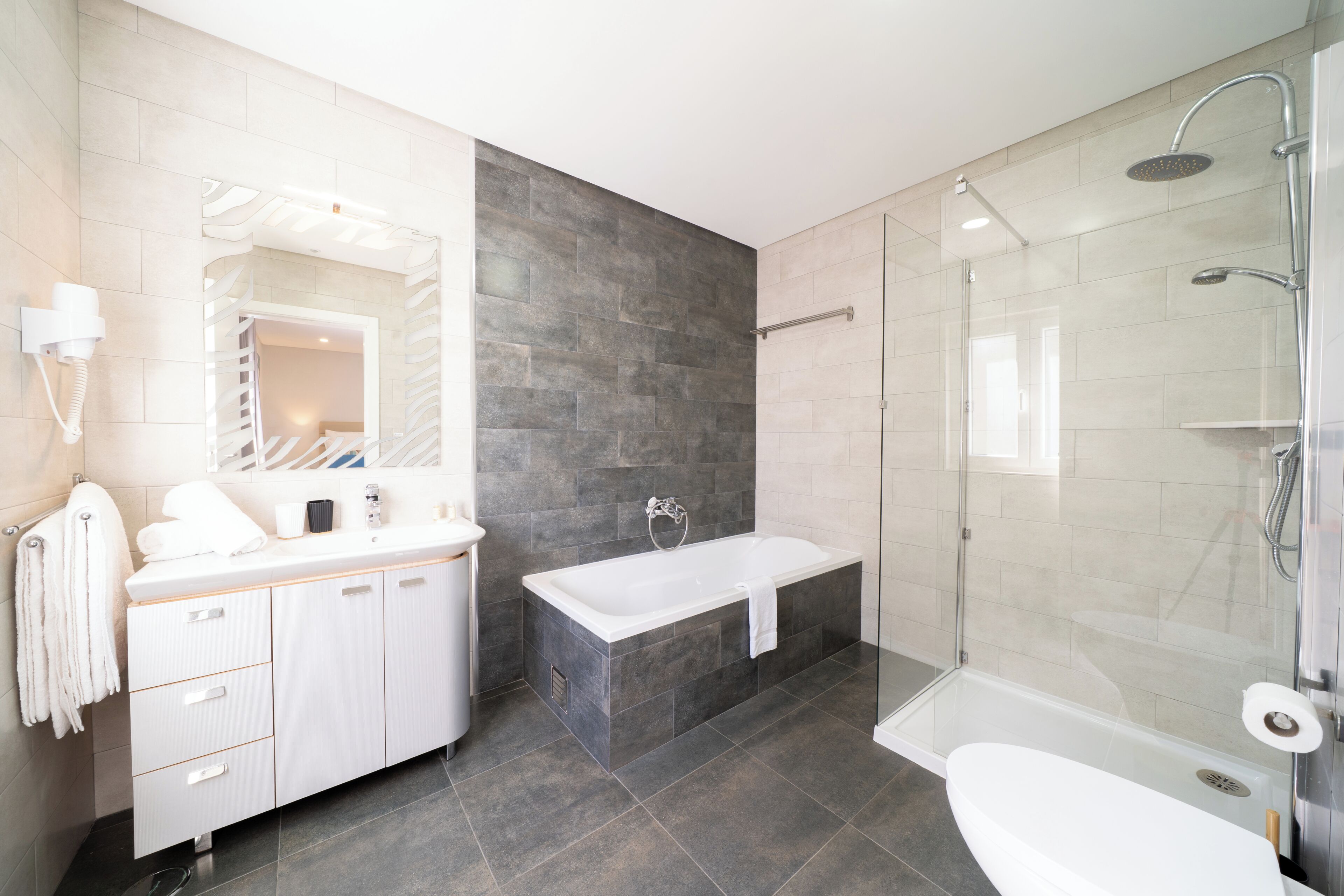 A modern bathroom with a white vanity, a freestanding bathtub, and a glass-enclosed shower area.