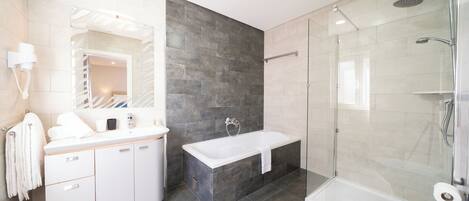 A modern bathroom with a white vanity, a freestanding bathtub, and a glass-enclosed shower area.