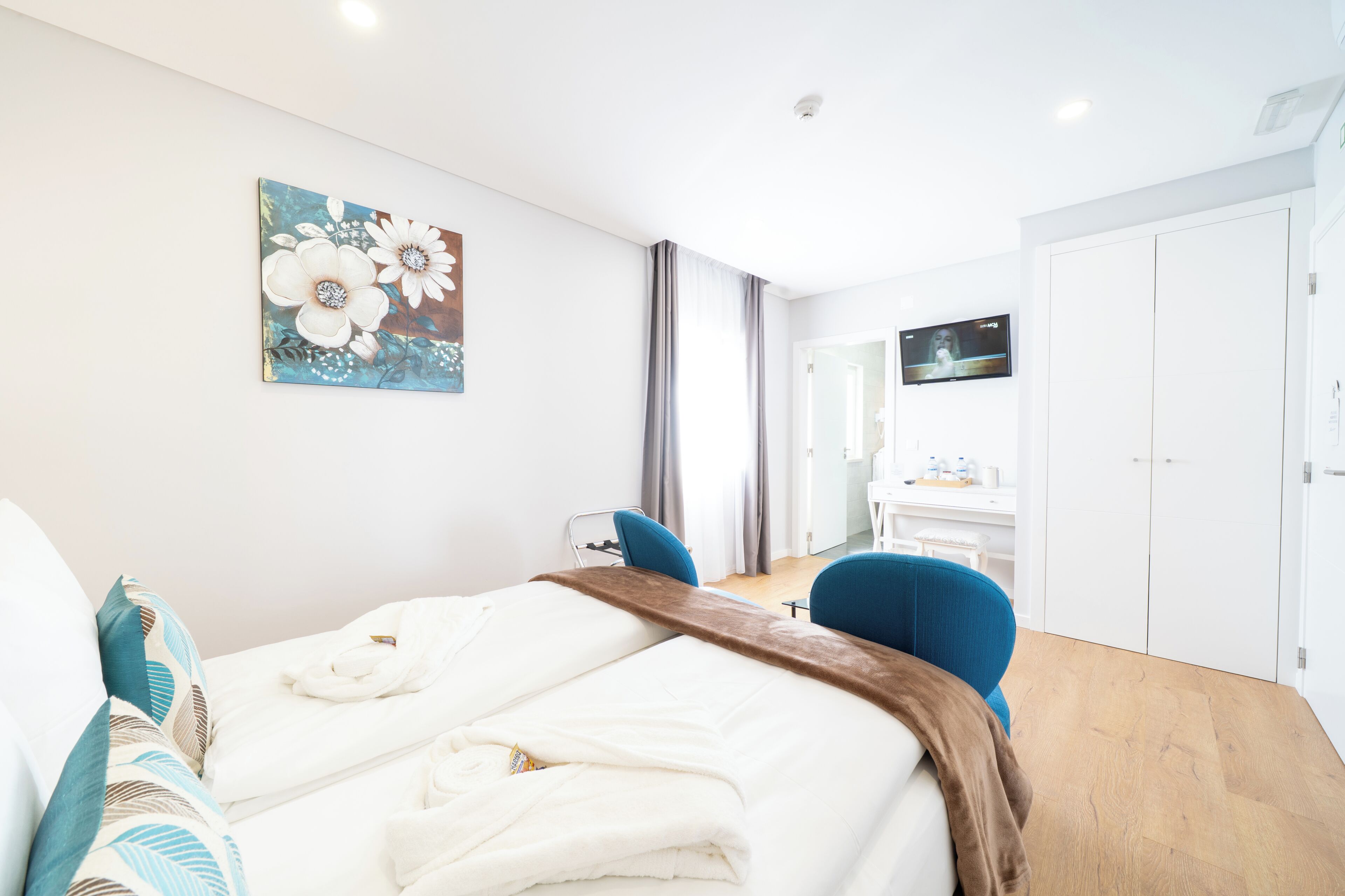 Una habitación de hotel con cama, escritorio, silla, televisor y armario.