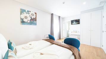 Una habitación de hotel con cama, escritorio, silla, televisor y armario.