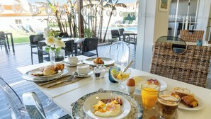 Una mesa de desayuno con platos de comida, un vaso de jugo de naranja y una cesta de mimbre.