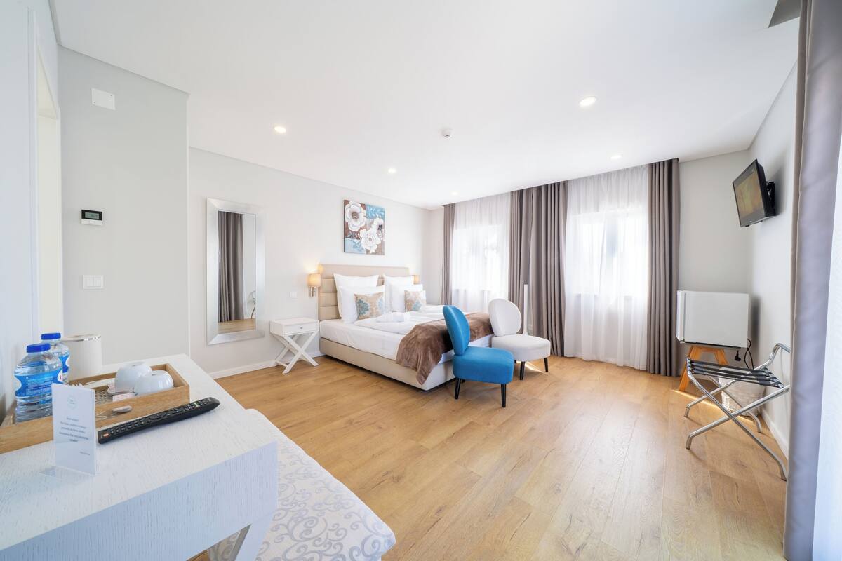 Een moderne hotelkamer met een bed, een bureau, een stoel, een televisie en een raam met gordijnen.