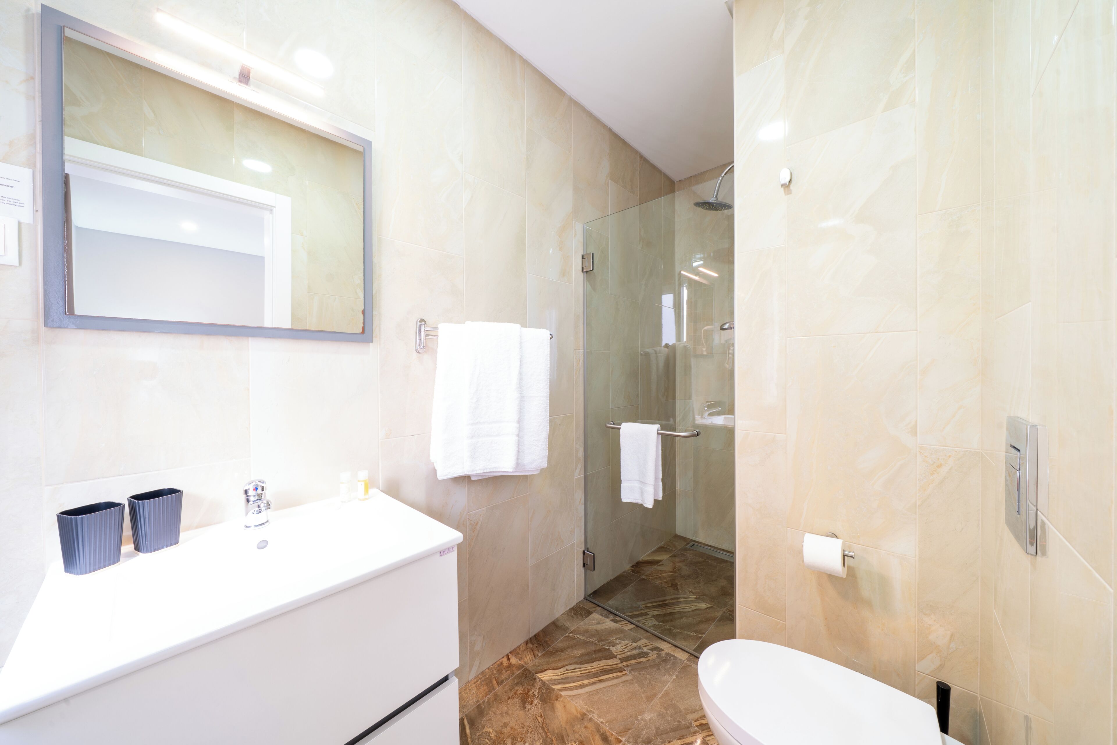 A modern bathroom with a glass-enclosed shower, a white sink, and a large mirror.