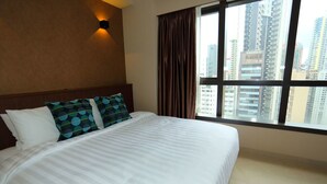 A hotel room with a large bed, a view of tall buildings, and a window with curtains. - WE Hotel (Hong Kong)