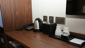 A hotel reception desk with a telephone, coffee maker, and a tray with cups and a notepad. - WE Hotel (Hong Kong)