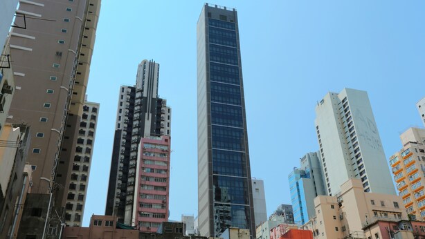 A high-rise building with a modern glass facade, surrounded by other buildings of varying heights and architectural styles. - WE Hotel (Hong Kong)