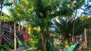 A wooden deck with a hammock, a bench, and a table. - Hotel Pousada Marambaia (Porto Seguro)