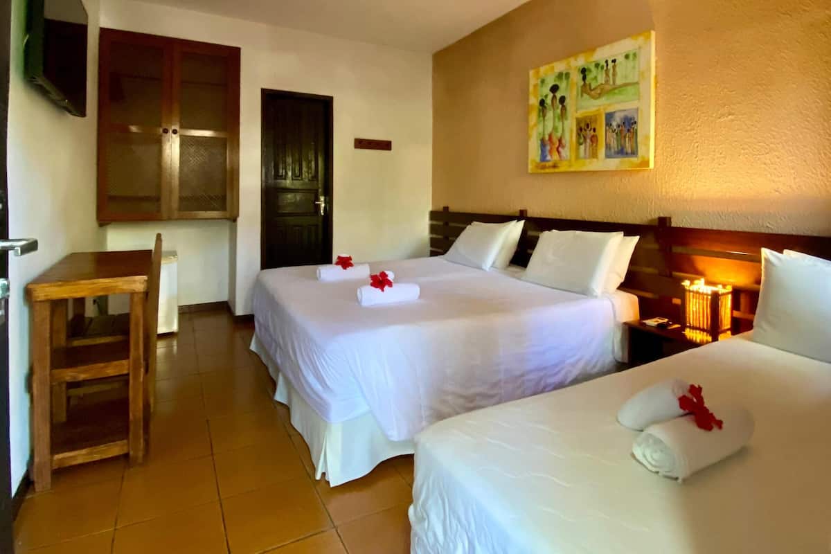A hotel room with two beds, a desk, a chair, and a TV mounted on the wall.