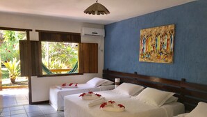 A hotel room with two beds, a large window, a painting on the wall, and a view of greenery outside. - Hotel Pousada Marambaia (Porto Seguro)