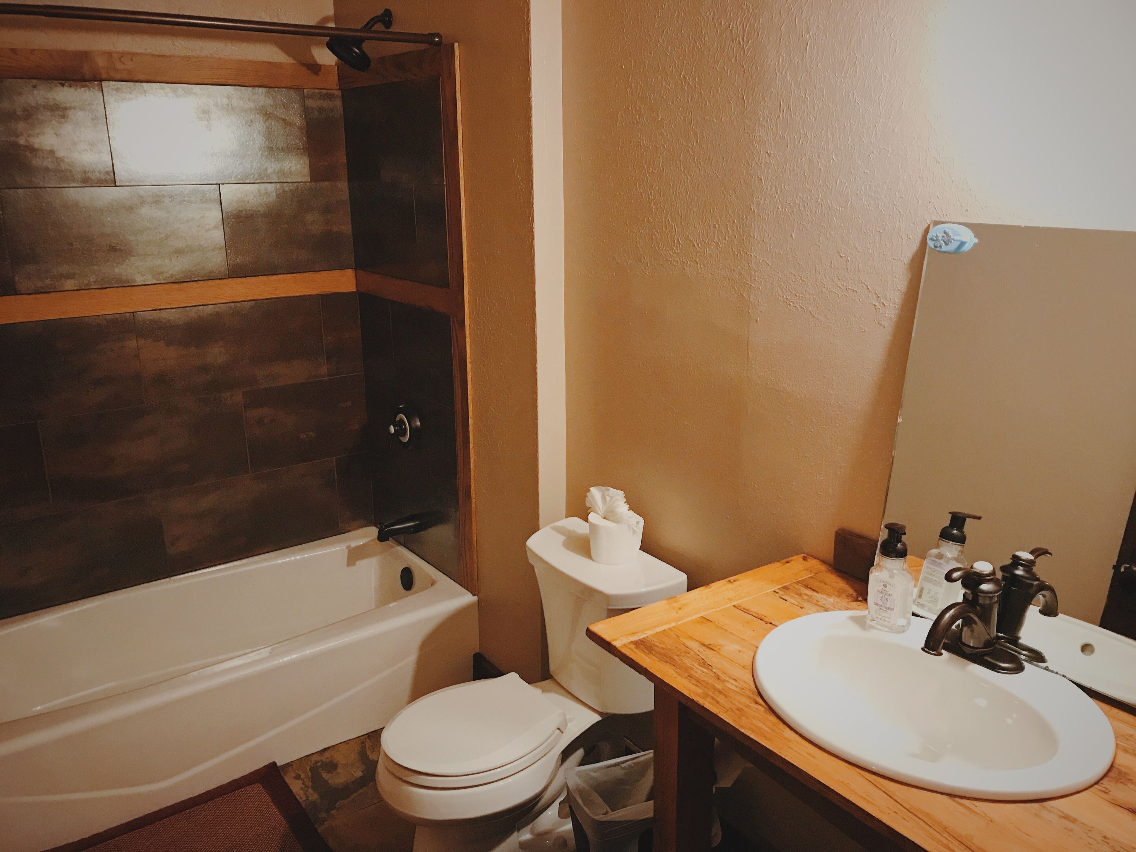 A bathroom with a bathtub, toilet, sink, and mirror.