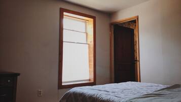 A bedroom with a bed, a window, and a door.