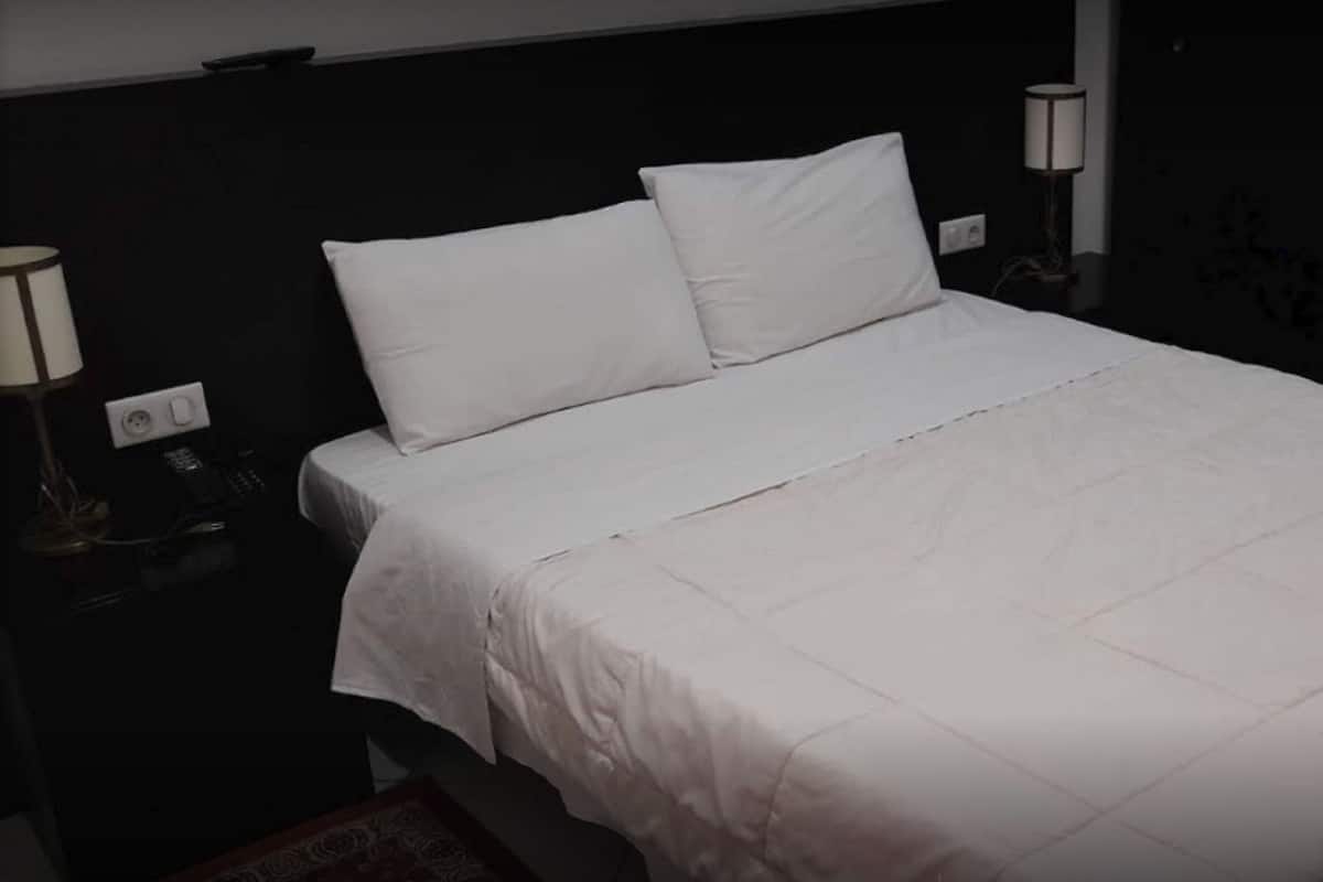 Una cama bien hecha con ropa de cama blanca en una habitación de hotel.