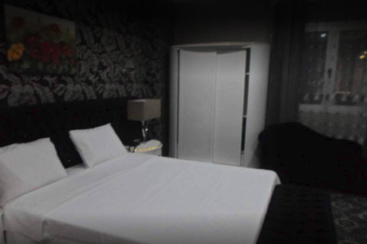 Una habitación de hotel con cama, mesita de noche, lámpara y puerta.