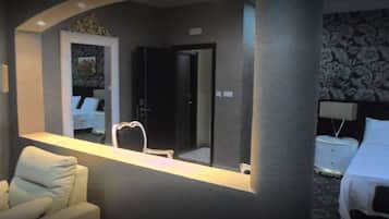 Ein Hotelzimmer mit einem großen Spiegel, einem weißen Bett, einem Nachttisch mit Lampe und einem Sessel.