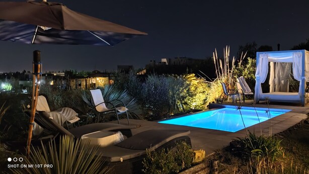 A nighttime outdoor pool area with lounge chairs, a canopy, and a tent. - Casa Laderas de Chacras de Coria (Chacras de Coria)