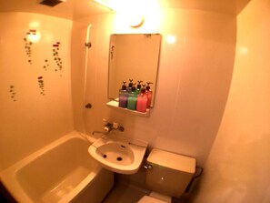 Un baño con bañera, lavabo, inodoro y un espejo sobre el lavabo.