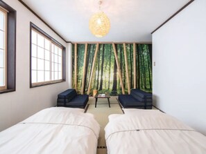 Une chambre avec deux lits, une table et des chaises, et une fresque représentant une forêt de bambous sur le mur.