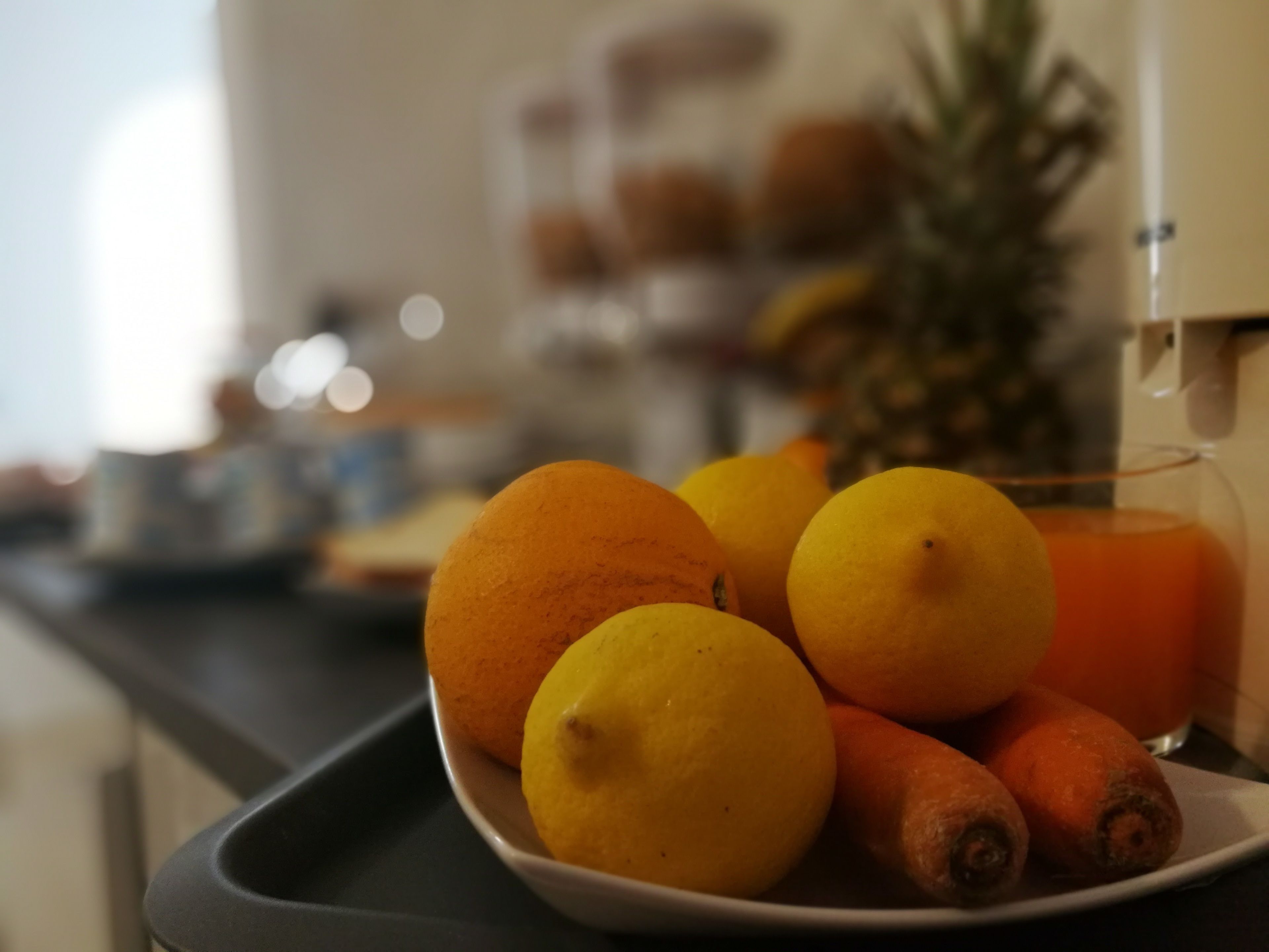 Een dienblad met sinaasappels, citroenen en een ananas op een aanrecht.