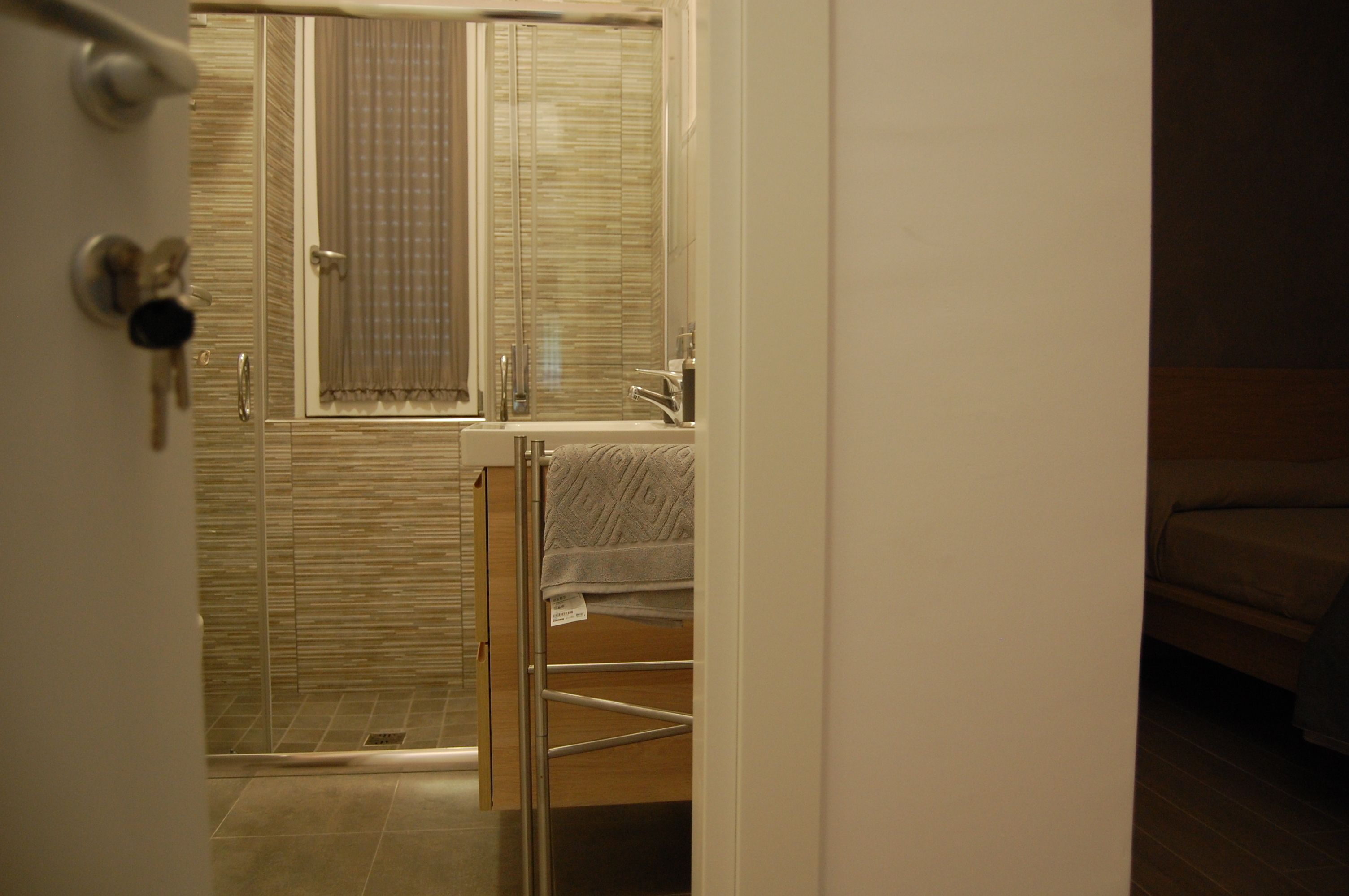 A bathroom with a glass shower enclosure, a sink, and a towel rack.