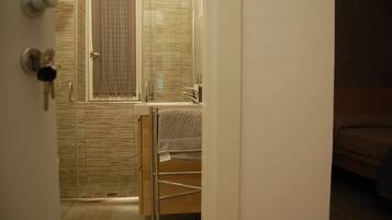 Un baño con cabina de ducha de vidrio, un lavabo y un perchero para toallas.