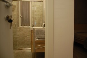 Un baño con cabina de ducha de vidrio, un lavabo y un perchero para toallas.