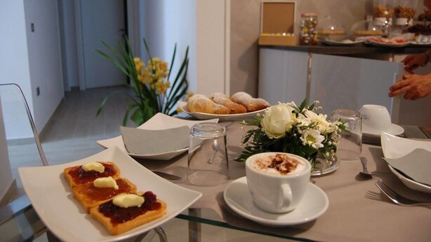 A breakfast setting with pastries, a coffee cup, and a flower arrangement on a table. - B&B da Francesco (Capaccio-Paestum)