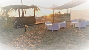 A beachside seating area with white plastic chairs and a thatched structure. - B&B da Francesco (Capaccio-Paestum)