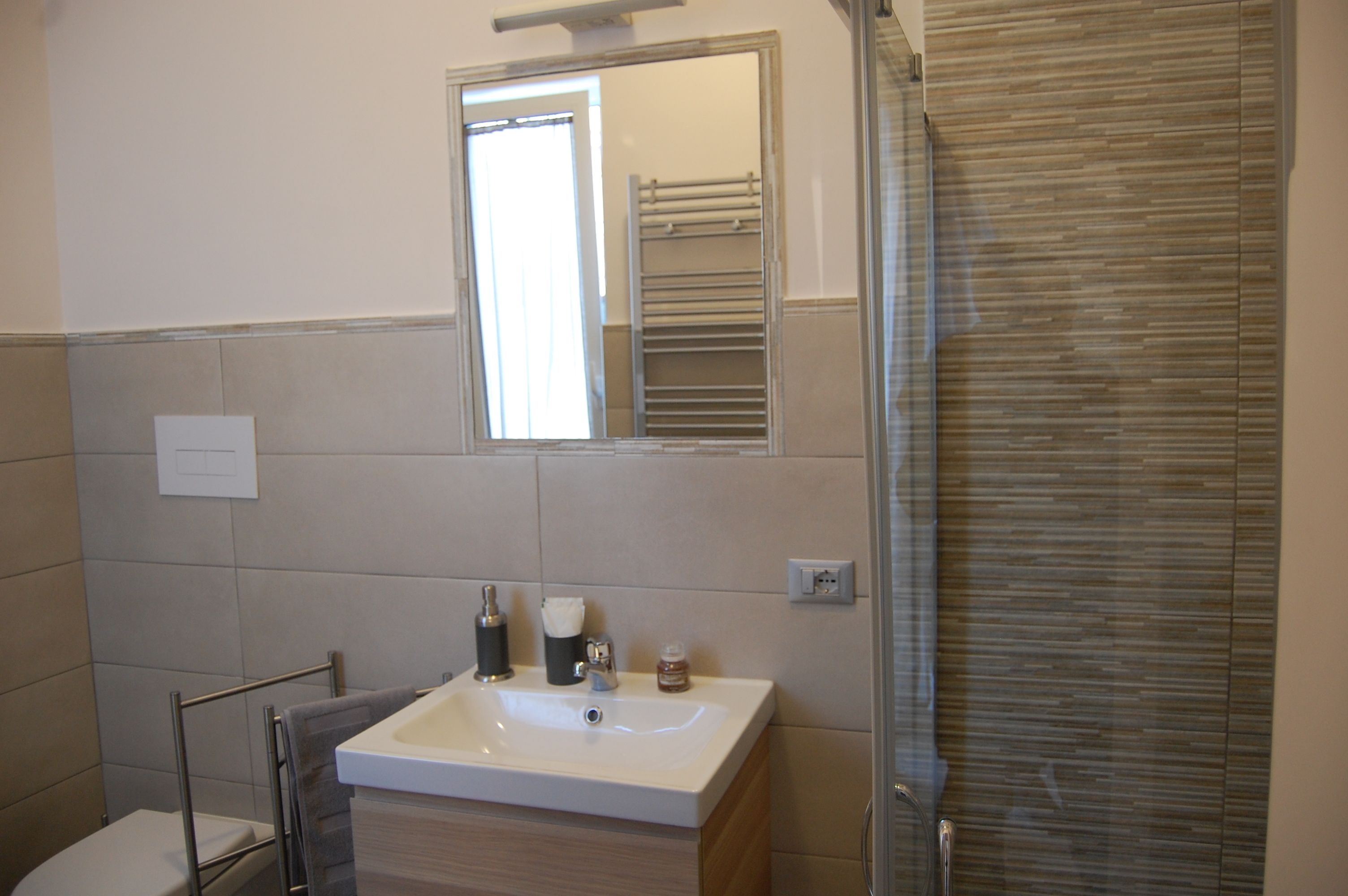 A bathroom with a white sink, a mirror, a towel rack, and a shower area.
