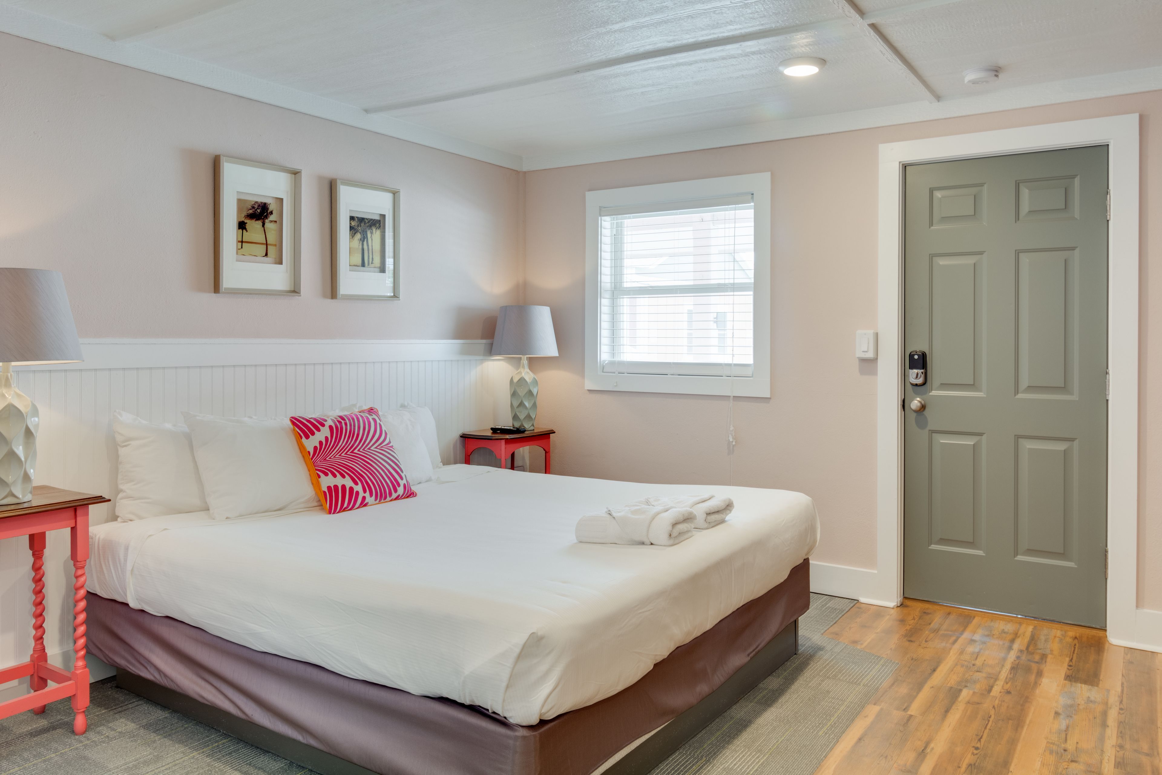 A neatly arranged bedroom with a bed, bedside tables, a door, and a window.