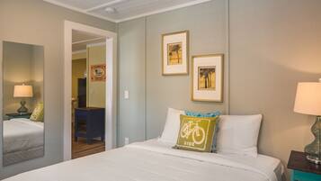Een hotelkamer met een bed, een nachtkastje met een lamp, een spiegel en twee ingekaderde foto's aan de muur.