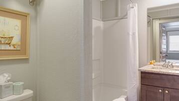 Een badkamer met douche, toilet en wastafel.